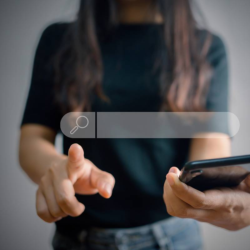 A woman holding a smartphone, embarking on a quest for the best system.