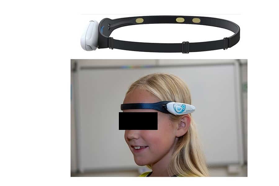 A young individual wearing a head-mounted device with an adjustable strap and a white, futuristic-looking gadget positioned over the forehead, possibly for virtual reality, augmented reality experiences, or non-invasive neurotechnology applications